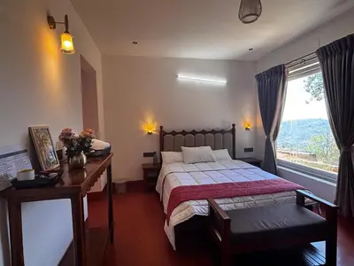 a bedroom with a bed and a desk and a window at Burnside Cottage in Kotagiri