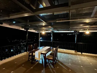 a table and chairs on a balcony at night at Burnside Cottage in Kotagiri