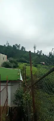 a fence with a green hill in the background at Bison valley in Ooty
