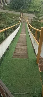 a walkway with green grass on the side of a bridge at Bison valley in Ooty