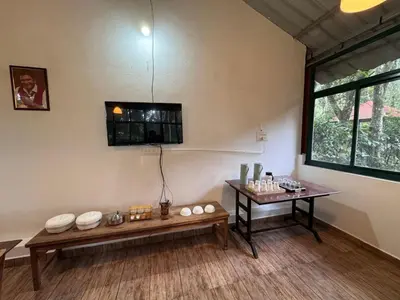 a room with two benches and a table and a window at Manuvan Estate Stay in Kushālnagar