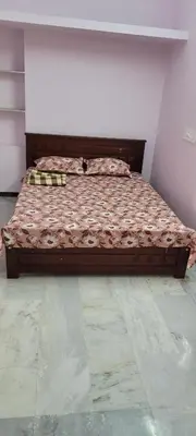 a large bed in a room with a bed frame at Sri Kamakshi Amman Home Stay in Tudiyalūr