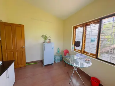 a kitchen with a glass table and a refrigerator at Whitelily's Amrithasthanam in Madikeri