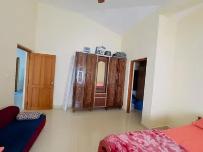 a room with a bed and some wooden cabinets at Whitelily's Amrithasthanam in Madikeri