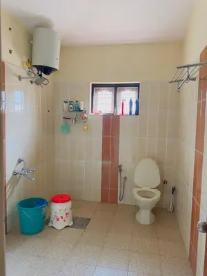 a bathroom with a toilet and a window at Whitelily's Amrithasthanam in Madikeri