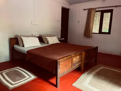 a bedroom with a bed with a wooden table and a window at Tranquilandia in Varagampadi