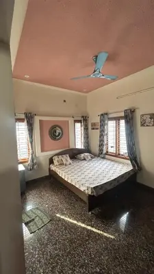 a bedroom with a bed and two windows at Aalaya in Mysore