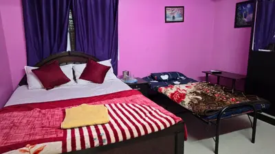 a bedroom with pink walls and a bed and a table at Ooty Individual Villa in Ooty