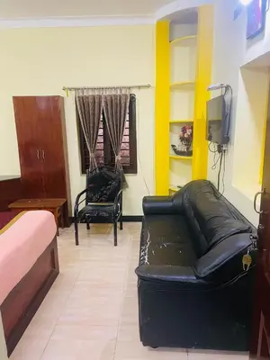 a living room with a black leather couch and a chair at budget stay-mystique inn in Ooty