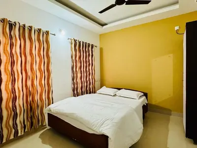 a bedroom with a bed and a window with curtains at Anandha Vibes STAY blessed in Guruvāyūr