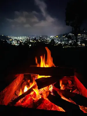 a fire pit at night with a city in the background at RS Hollidays ooty in Ooty