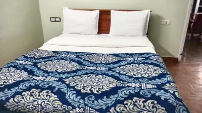 a bed with a blue and white quilt on it at RS Hollidays ooty in Ooty