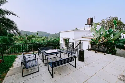 a patio with a table and chairs and a house at Alora villas in Wayanad