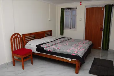 a bedroom with a bed and a chair and a window at Kitty Royal Inn in Ooty