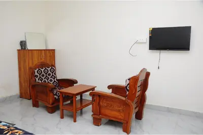 a room with two chairs and a flat screen tv at Kitty Royal Inn in Ooty