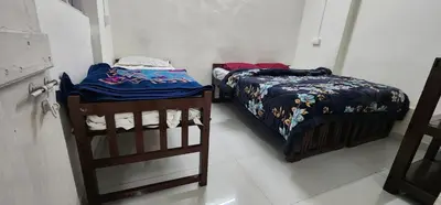 a bedroom with two beds and a ladder next to it at Kitty Royal Inn in Ooty