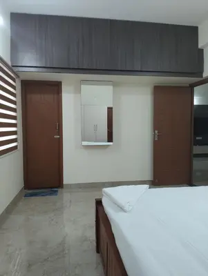a bedroom with a large bed and two wooden doors at Amaira Studio living - Coimbatore in Coimbatore