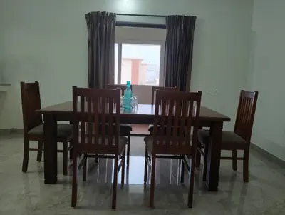 a dining room table and chairs with a window at Amaira Studio living - Coimbatore in Coimbatore