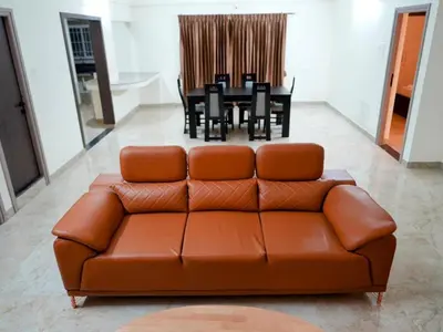 a brown leather couch in a living room with a table at Amaira Studio living - Coimbatore in Coimbatore