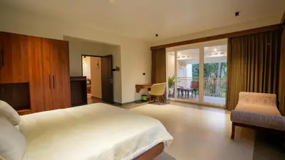 a bedroom with a bed and a desk and a balcony at Mizuki Homestay in Trichūr