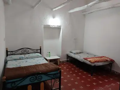 a bedroom with two beds and a table in it at Nalee Farm Stay in Hunsūr
