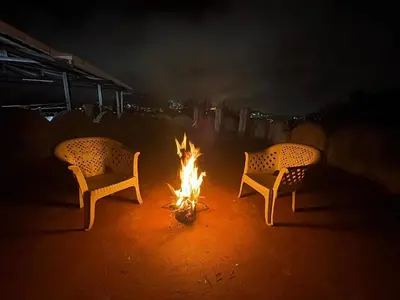 two chairs sitting around a fire in the dark at The Hill Bunk Heights Ooty in Ooty