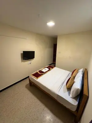 a bedroom with a bed with a tv on the wall at The Hill Bunk Heights Ooty in Ooty