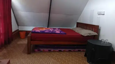 a small bedroom with a bed with a red blanket at Vattavada budget cottages & Aframe in Vattavada