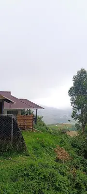 a house on a grassy hill with a building at Vattavada budget cottages & Aframe in Vattavada