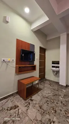 a room with a table and a tv on a wall at Azhagumail Honey Resort Kanthalloor in Kanthalloor