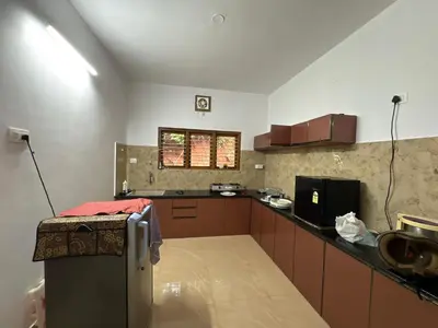 a kitchen with a refrigerator and a counter top at sireesha estate cottage stay in Madikeri