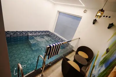 a swimming pool in a room with chairs and a window at Palm Wave Beach Resort in Cherai Beach