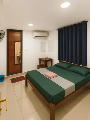 a bedroom with a large bed with a blue curtain at RJ Residency in Kozhikode