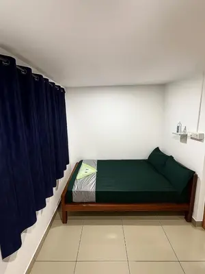 a bedroom with a green bed and blue curtains at RJ Residency in Kozhikode