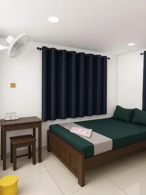 a bedroom with a bed and a table and a curtain at RJ Residency in Kozhikode