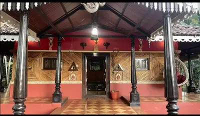 a building with a red wall and a door with columns at NATUREs LAP FARM STAY Mysore in Mysore