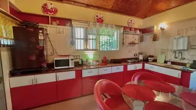 a red and white kitchen with red chairs and a table at NATUREs LAP FARM STAY Mysore in Mysore
