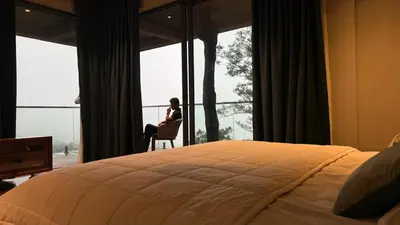 a woman sitting in a chair in front of a window at Vythiri Waves Resort l 3BR Private Pool Villa in Vayittiri
