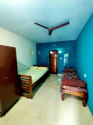 a bedroom with two beds and a ceiling fan at Aiyappa Stayz in Madikeri