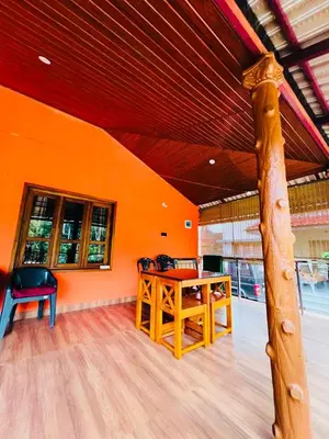 an orange room with a wooden table and chairs at Aiyappa Stayz in Madikeri