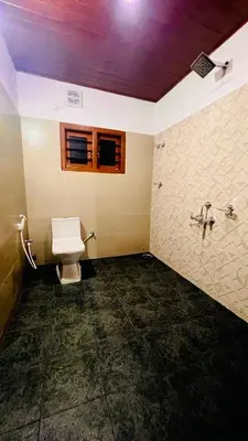 a bathroom with a toilet and a window at Aiyappa Stayz in Madikeri