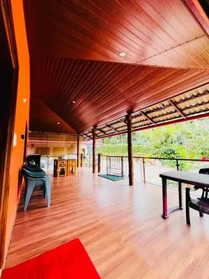 a large room with a wooden floor and a table at Aiyappa Stayz in Madikeri