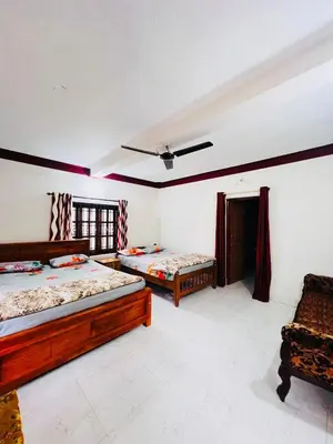 a bedroom with two beds and a couch in it at Aiyappa Stayz in Madikeri