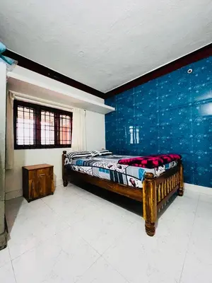 a bedroom with a bed and a blue wall at Aiyappa Stayz in Madikeri