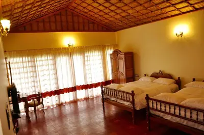 a bedroom with two beds and a large window at Hanging Huts Resorts in Kotagiri
