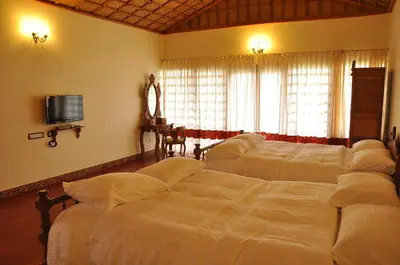a bedroom with two beds and a flat screen tv at Hanging Huts Resorts in Kotagiri