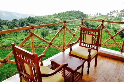 two chairs on a porch with a view of a mountain at Hanging Huts Resorts in Kotagiri