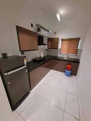 a kitchen with brown cabinets and a white tile floor at Rajagiri View Apartments in Alwaye