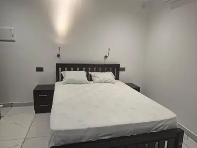 a bedroom with a large bed with white sheets at Rajagiri View Apartments in Alwaye