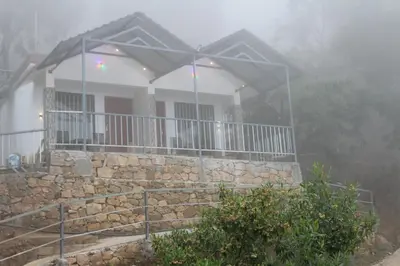 a house on a mountain in the fog at Amber Mount Resorts in Kanthalloor